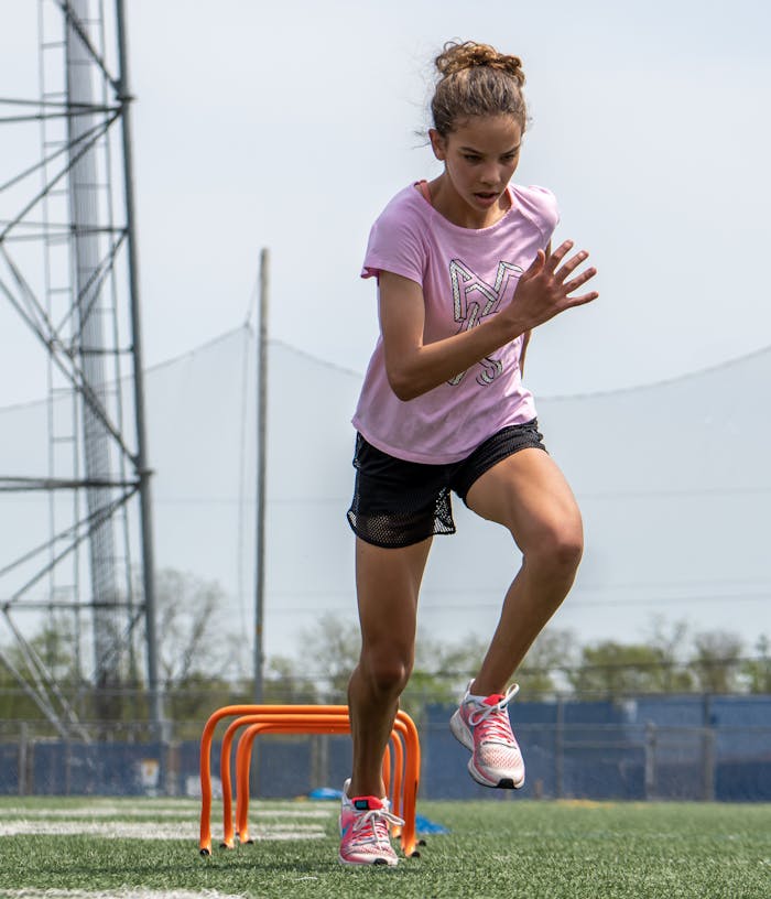 A woman performs hurdle exercises outdoors, emphasizing fitness and healthy lifestyle.