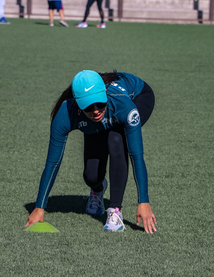 Female athlete in athletic attire preparing to sprint on a sports field.